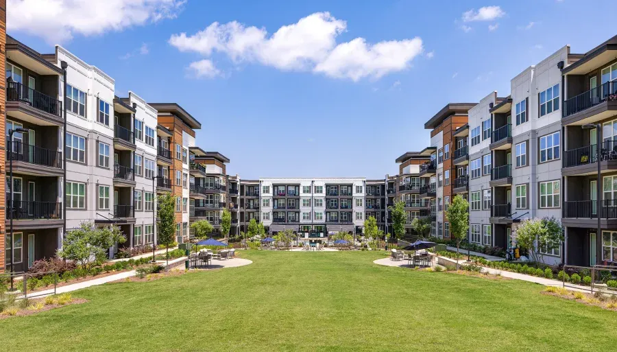 The central courtyard at The Ellison at Mallard Creek in Charlotte, North Carolina, with four-story residential buildings and their balconies framing an open lawn