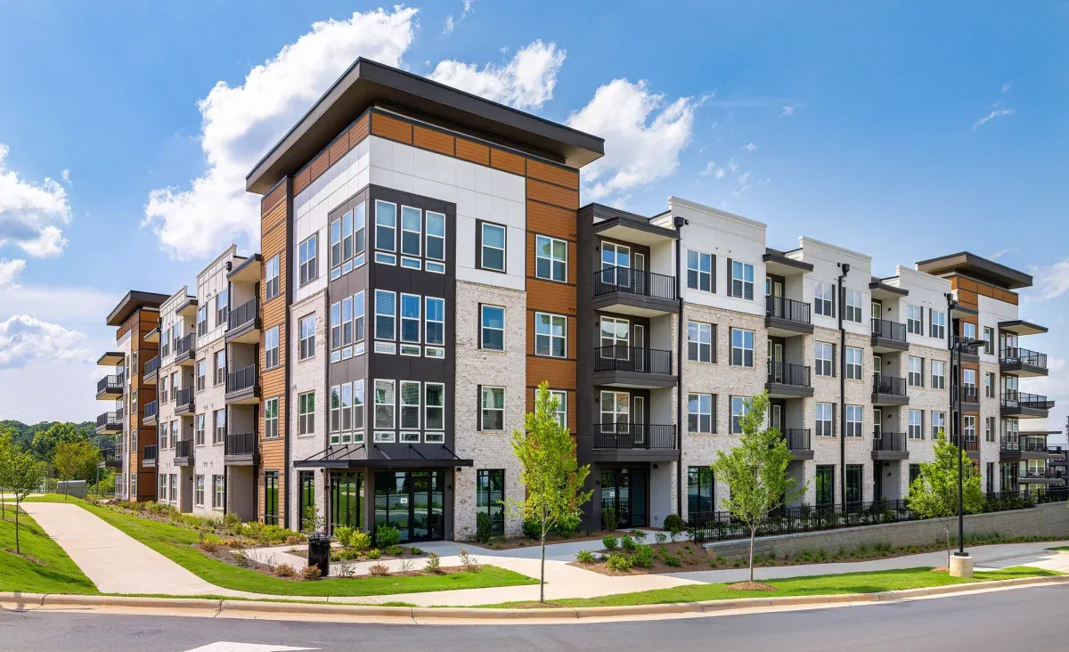 Ellison at Mallard Creek in Charlotte: a four-story apartment building in brick, stucco and wood, its corner stacked with black-framed windows