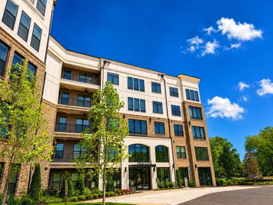 Rue 108 Apartments in Kennesaw, Georgia: a four-story brick and stucco building with black-framed windows and balconies, above the signed glass entrance