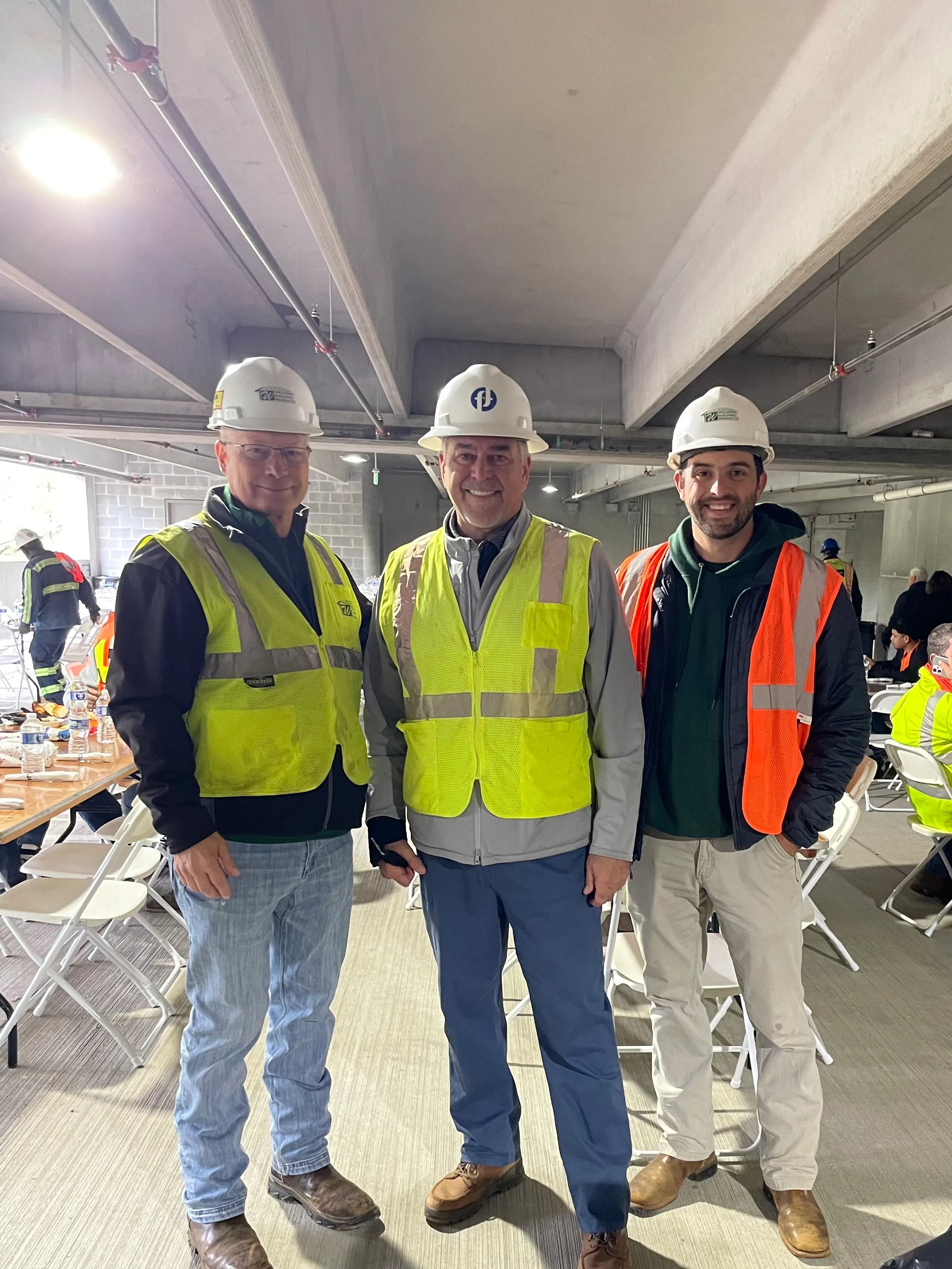 Three men in hard hats and safety vests on a jobsite with general contractor Fortune Johnson